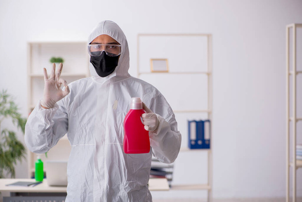 Jeune entrepreneur désinfectant son bureau pendant une pandémie - Photo, image