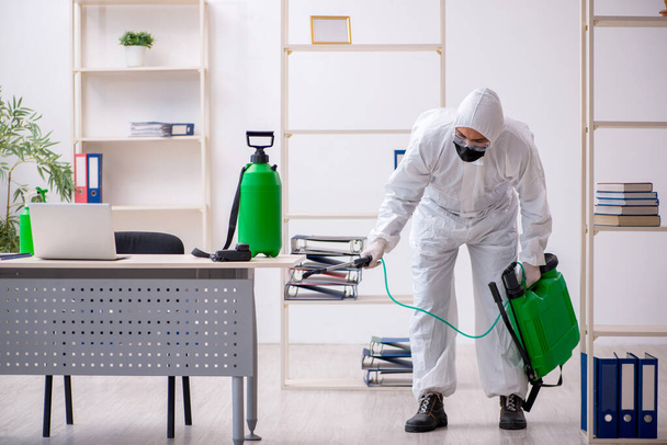 Young male contractor disinfecting office during pandemic - Φωτογραφία, εικόνα