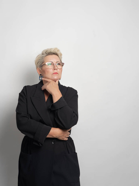 Adult woman with short hair, blonde. with glasses posing at the camera. There is a light background in the studio. Close-up. - Φωτογραφία, εικόνα