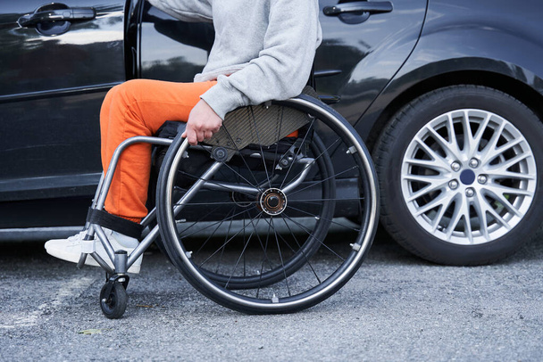 Молода дівчина з нижньою інвалідністю перемикає положення з інвалідного візка в автомобіль
 - Фото, зображення
