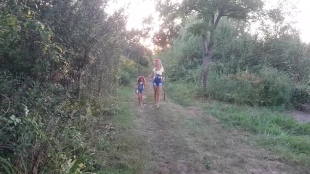 Mother and daughter return from fishing barefoot holding hands at sunset. Mom with a fishing rod, and daughter with a bucket. - Footage, Video