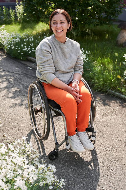 Woman with lower body disability smiling toothy while sitting at the wheelchair - 写真・画像