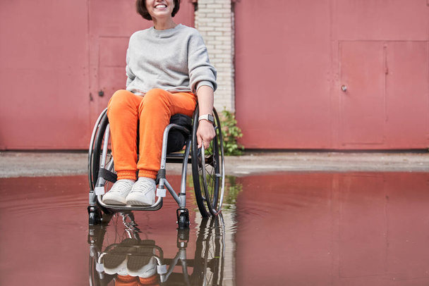 Disabled woman rejoicing of the rainy weather while sitting at the wheelchair and walking - Фото, зображення