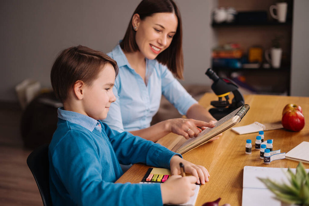 Thuis leren, vrouw en jongen studeren aan tafel - Foto, afbeelding