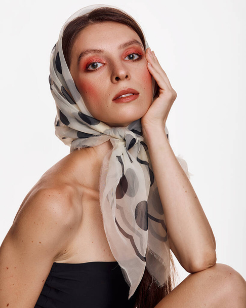 Portret van een jonge vrouw in een modieuze hoofddoek. Helder huidmodel met roze make-up. Schoonheid, mode, huidverzorging en Spa concept op witte achtergrond. - Foto, afbeelding