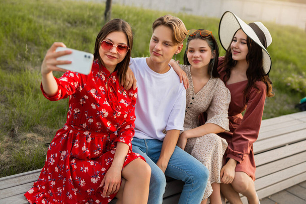 beautiful young friends are photographed on the phone in the summer park - Zdjęcie, obraz