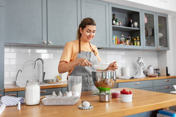 happy young woman cooking food on kitchen at home - Foto, Bild