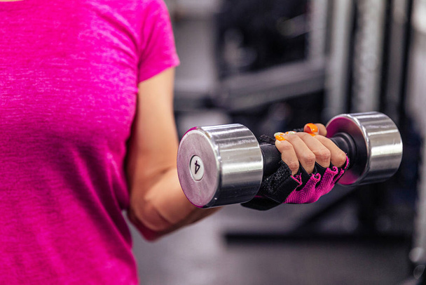 Exercise with dumbbells. A woman's hand with dumbbells. Close-up. Gym - Фото, изображение