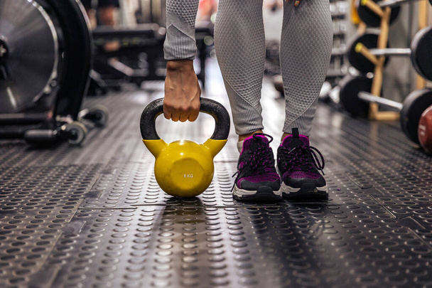 Close-up: A kettlebell in the hand next to the legs. Gym - Фото, зображення