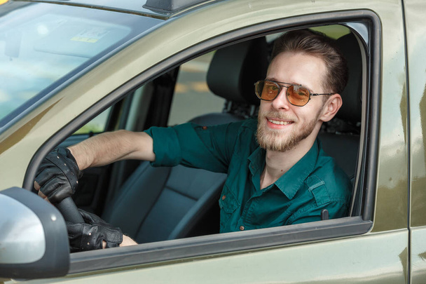 Portrait of a young man in dark glasses driving a car and smiling - Fotografie, Obrázek