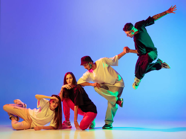 Gruppe junger Leute, Jungs und Mädchen in zeitgenössischem Tanz, Hip-Hop, Bremstanz vor blauem Hintergrund im Neonlicht. - Foto, Bild