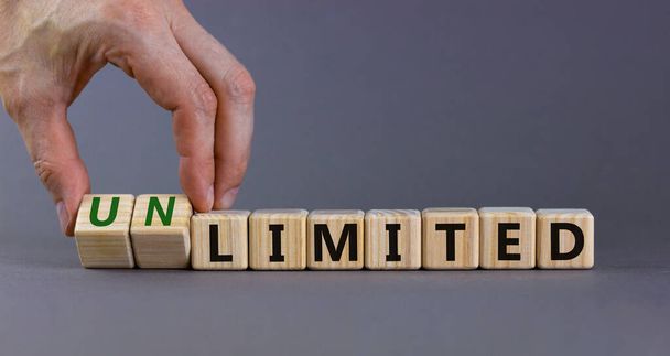 Limited or unlimited symbol. Businessman turns cubes, changes words 'limited' to 'unlimited'. Beautiful grey background, copy space. Business, limited or unlimited concept. - Photo, image