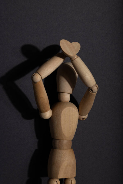 Dřevěná figurína stojí se zdviženýma rukama na šedém pozadí. protest, koncept pozornosti. kopírovat prostor, tvrdé světlo. - Fotografie, Obrázek