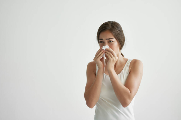 Frau im weißen T-Shirt pustet sich bei Kopftuch-Infektion die Nase zu - Foto, Bild