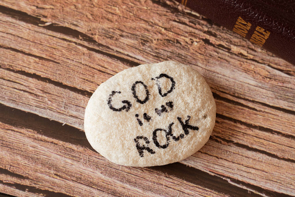 God is my Rock and my salvation. Jesus Christ is my fortress, Deliverer, and Savior. Firm faith, hope, love, and trust in the LORD. Handwritten quote on stone with Holy Bible. Biblical concept. Closeup - Photo, Image