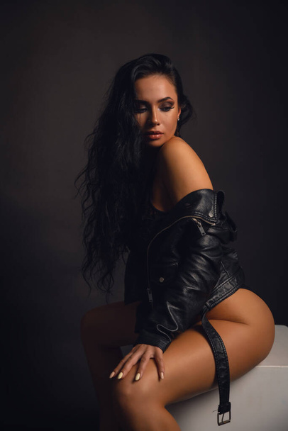 Beautiful stylish woman wearing black leather jacket. Fashionable and self-confident girl with long curly hair. Clothing, style and fashion - Фото, изображение