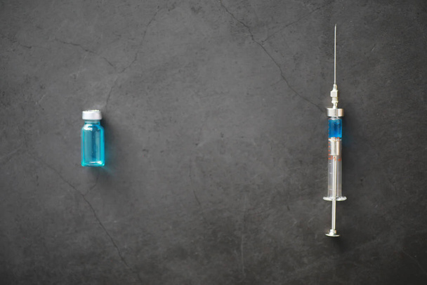 маленькие банки с инъекцией и шприц для инъекций на синем фоне рядом с химическим формулом - Фото, изображение