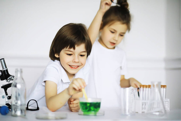 Dos niños lindos en la lección de química haciendo experimentos aislados en el fondo blanco - Foto, imagen