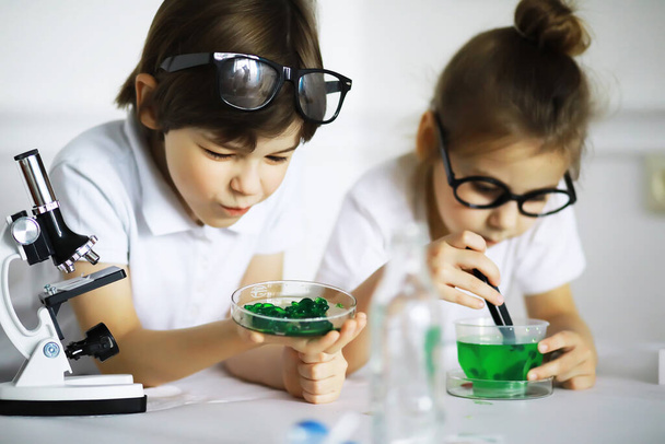 Zwei süße Kinder im Chemieunterricht machen Experimente auf weißem Hintergrund - Foto, Bild