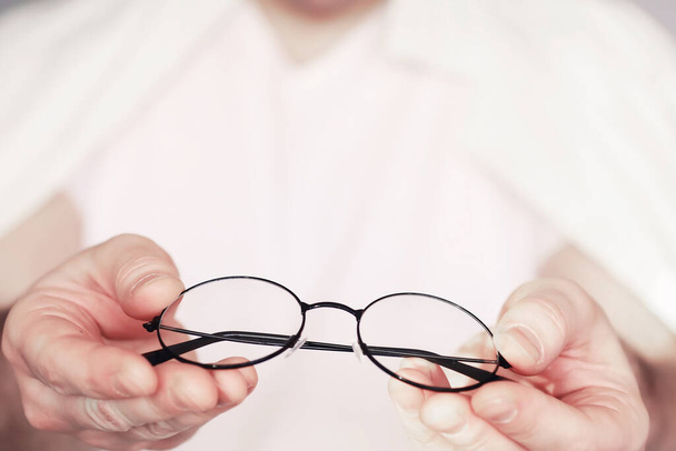Het concept van slecht zicht. Houd een contactlens en bril in de hand. Affiche voor reclamebrillen en -lenzen. - Foto, afbeelding