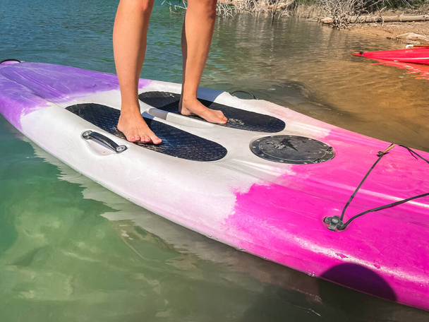 Beautiful and strong woman on a sup board and enjoying turquoise transparent water in the lake. Tropical travel, wanderlust and water activity concept. Paddle Surf water sports. Summer vacations. - Φωτογραφία, εικόνα