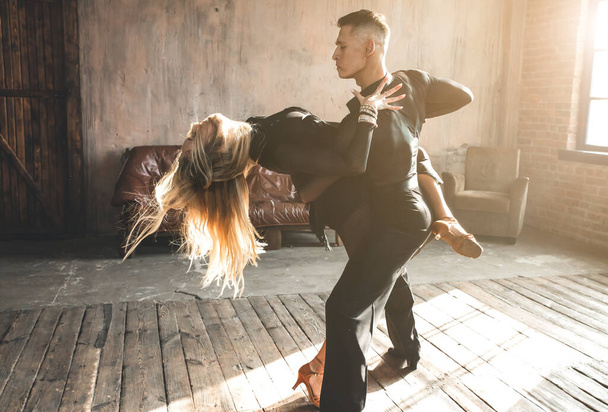 Un par de bailarines de salón profesionales bailan en el estudio loft. Hermosa actuación artística. Concepto de vida deportiva. Pasión y danza emocional. - Foto, imagen