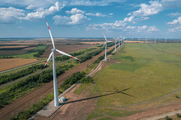 Aerial view of Wind power turbine is a popular sustainable, renewable energy source on beautiful cloudy sky. Wind power turbines generating clean renewable energy for sustainable development. - Photo, Image