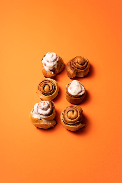 Freshly baked cinnamon buns on an orange background top view. patern. copy space - Foto, Imagen