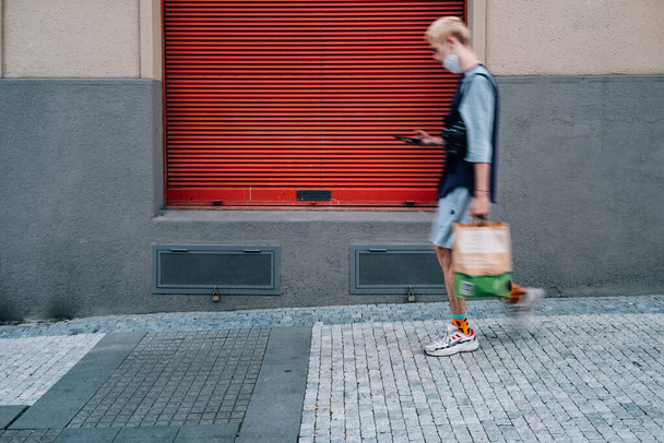 PRAGUE, CSEH KÖZTÁRSASÁG - 2021. július 20: Egy férfi sétál az utcán és ellenőrzi a telefonját - Fotó, kép