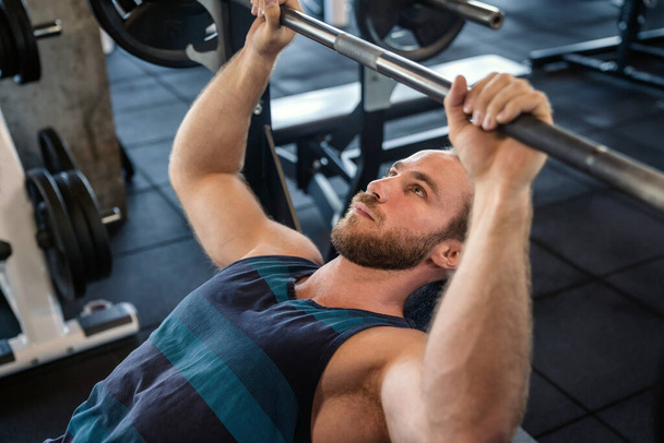 Handsome muscular fit man working out hard at gym - Photo, image