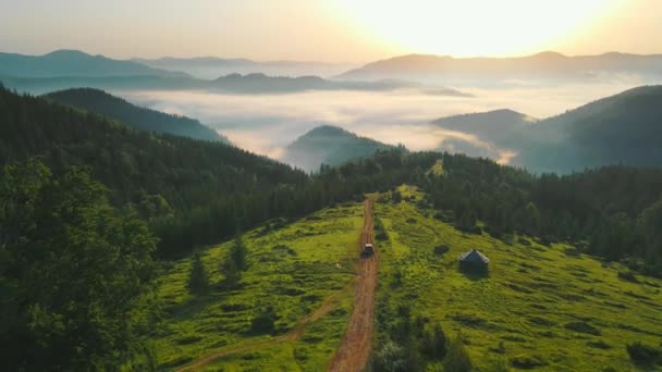 山の中で朝の風景。未舗装の道路を飛行し、渓谷に横たわっている日の出の美しい霧. - 映像、動画