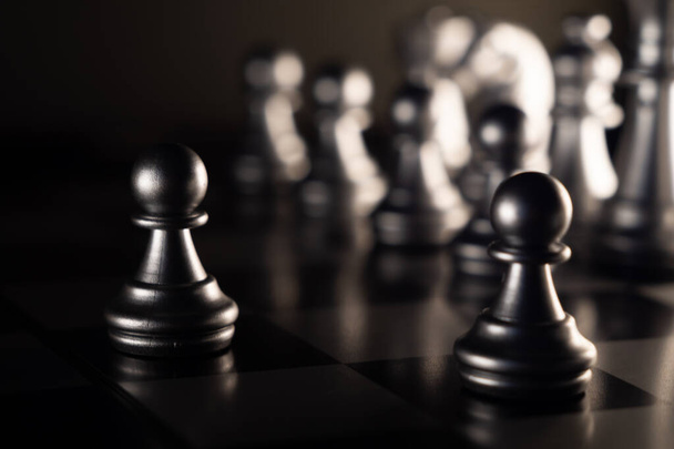 A selective-focus shot of black pawn chess pieces on the board - Photo, image