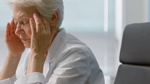 Женщина массирует виски, страдающие от головной боли в офисе - Кадры, видео
