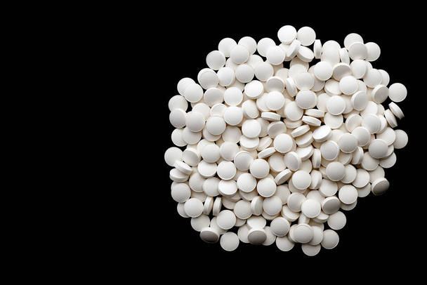 A shot of a pile of round-shaped white vitamin D pills on a black background. - Zdjęcie, obraz