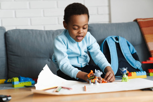 Black boy paying with toys while sitting on sofa at home - Φωτογραφία, εικόνα