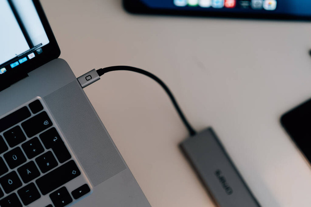 a top view of a gray laptop on the desk with a plugged black USB cable - Фото, изображение