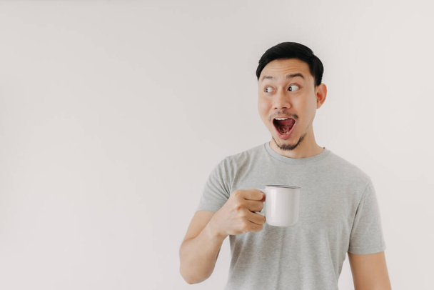 Surprised face of man drinks a cup of coffee isolated on white background. - Zdjęcie, obraz