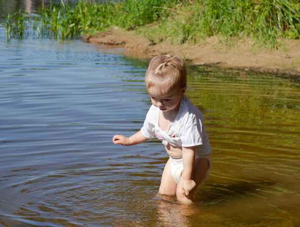 маленька дівчинка бризкає у воді біля берега
 - Фото, зображення