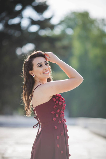 A beautiful Caucasian female from Bosnia and Herzegovina in an elegant burgundy dress with small roses - Foto, immagini