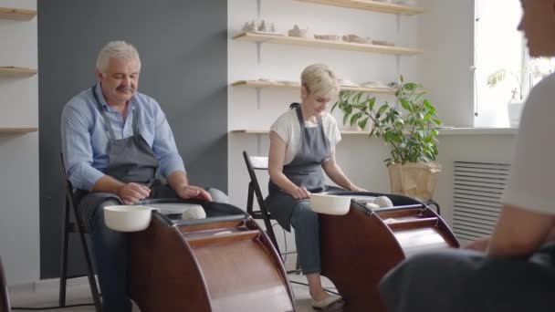 Una giovane donna insegna alla ceramica un gruppo di donne anziane e un uomo di 60-70 anni. Attività per anziani - Filmati, video