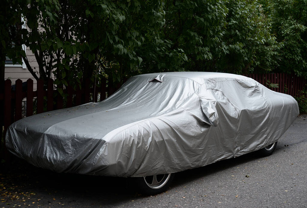 coche totalmente cubierto con una cubierta de plata, al aire libre - Foto, Imagen
