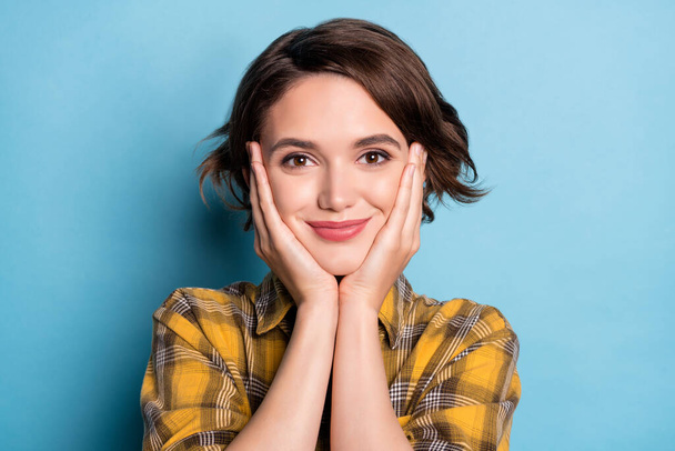 Photo of cheerful adorable girl hands cheekbones look camera wear plaid shirt isolated blue color background - Photo, Image
