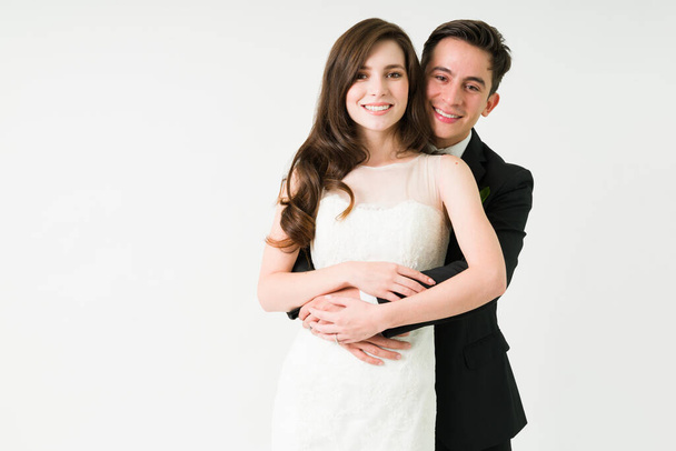 Portrait of a beautiful caucasian couple hugging and smiling. Young wife and husband feeling happy and in love after getting married - Photo, Image