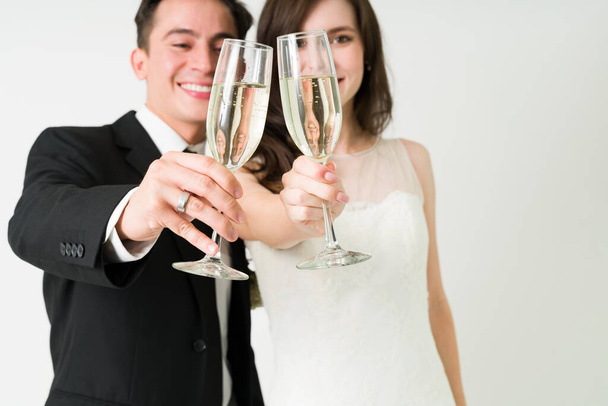 Σούπερ ενθουσιασμένοι νύφη και γαμπρός απολαμβάνοντας ένα ποτήρι σαμπάνια. Ελκυστικό ζευγάρι κάνει μια πρόποση και γιορτάζει το γάμο τους - Φωτογραφία, εικόνα