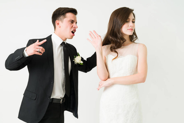 Annyira haragszom rád. Feldúlt férj fekete öltönyben kiabál a bosszús menyasszonyának az esküvői ceremónián. - Fotó, kép