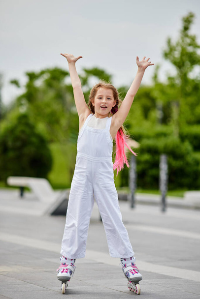 Cute little child girl on roller skates at park - Φωτογραφία, εικόνα