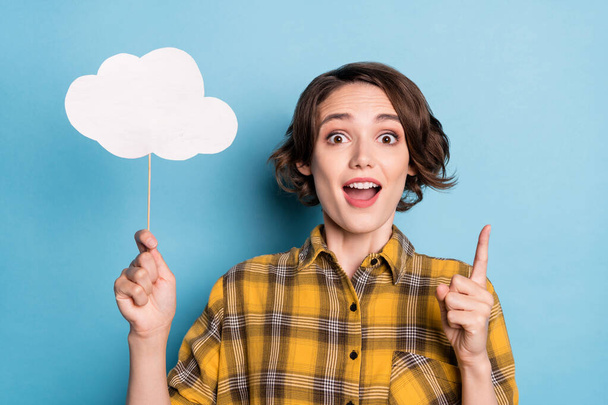 Photo of excited creative lady hold cloud card have great idea wear plaid shirt isolated blue color background - 写真・画像