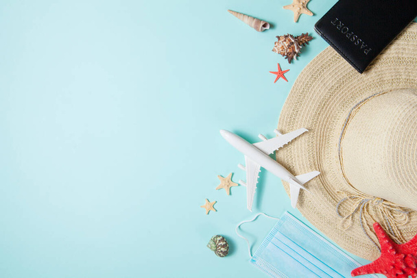 Optimistic coronavirus vacation concept. Summer 2021 vacation and travel background with sun hat, medical mask, passport, airplane and travel symbols flat lay. Waiting spring or summer time. - Foto, afbeelding