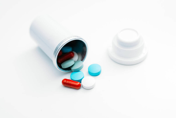 Vários medicamentos de comprimidos e comprimidos caem do recipiente sobre a mesa. - Foto, Imagem