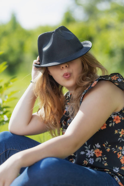 Portrait of bautiful young woman with pursed lips is posing in black hat Vertically.  - Photo, image